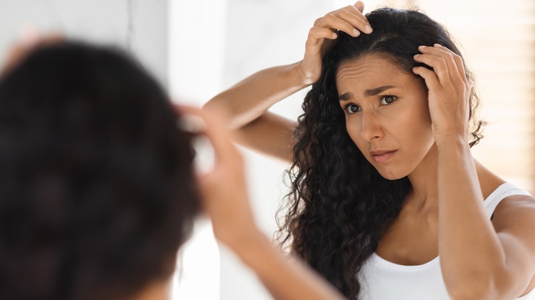 woman examining scalp in mirror