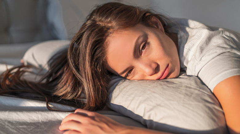 woman lying on pillow with sad look
