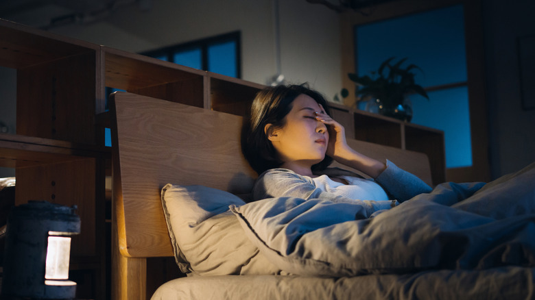 Woman up at night holding head