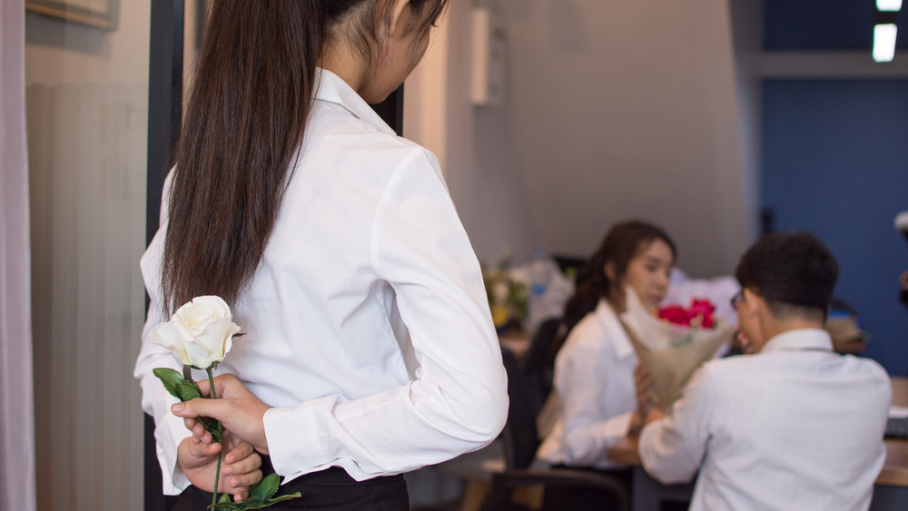 Woman watching her love give flowers to another woman