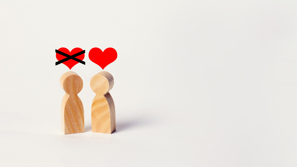 Wooden figures with hearts overhead one heart crossed out