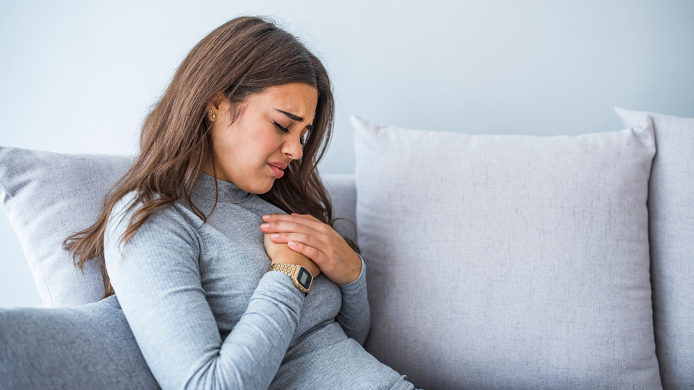 Woman experiencing heartburn while laying on couch