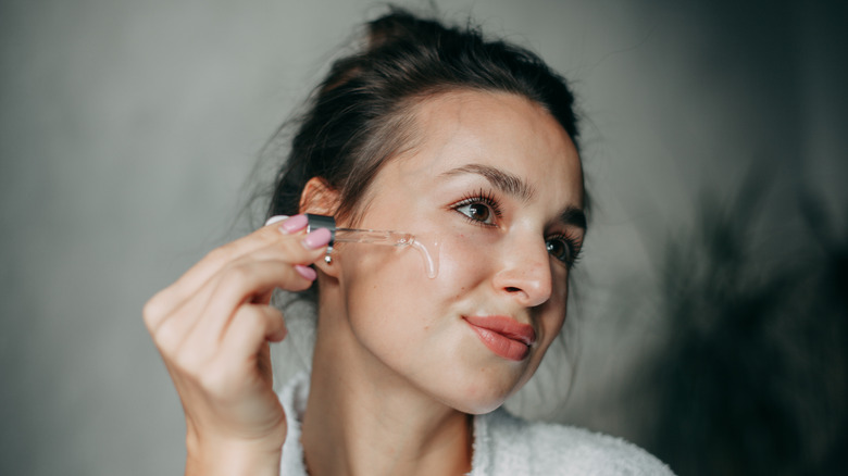 woman applying serum in bathroom