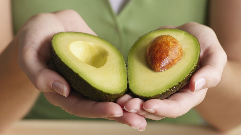 woman holding sliced avocado