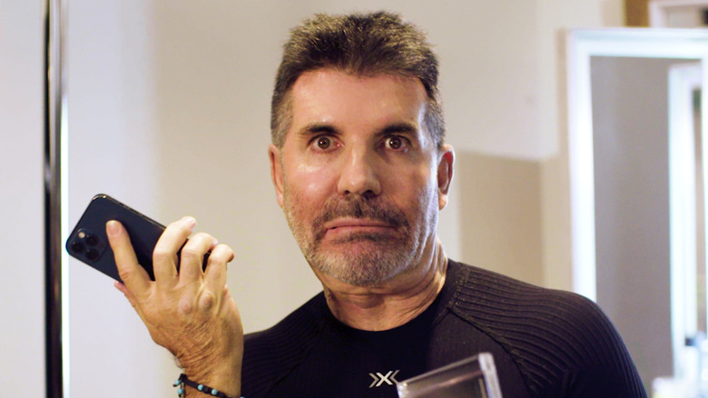 Simon Cowell frowning holding phone