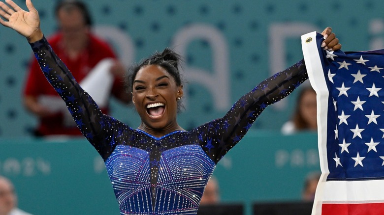 Simone Biles smiling, holding American flag