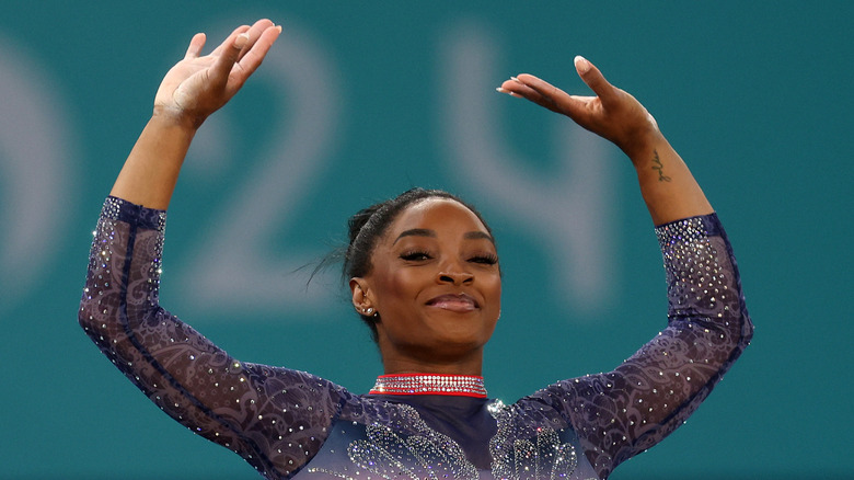 Simone Biles raising arms in a gymnastics leotard