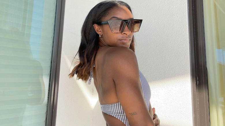 Simone Biles posing in a swimsuit and sunglasses