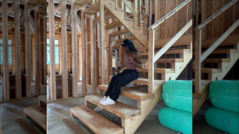 Simone Biles sits on the stairs of her unfinished house