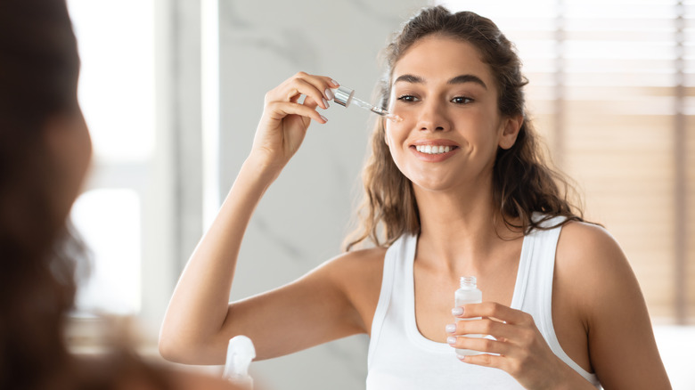 woman applying serum with eyedropper