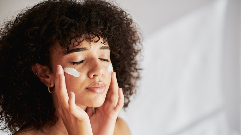 woman moisturizing face