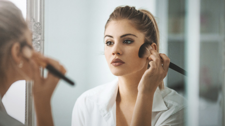 Woman applying powder to face