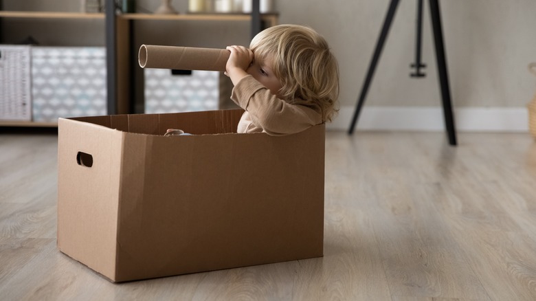 boy sitting in box, looking through tube