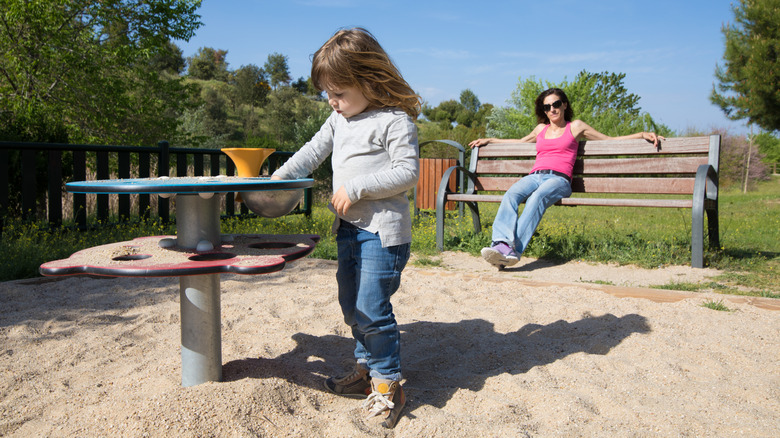 Child play sand playground mom sit bench