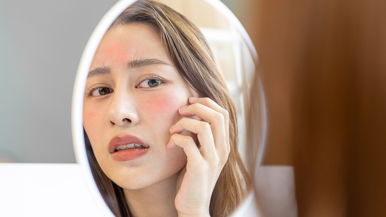 woman looking concerned into a mirror