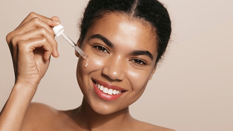 A woman applying serum. 