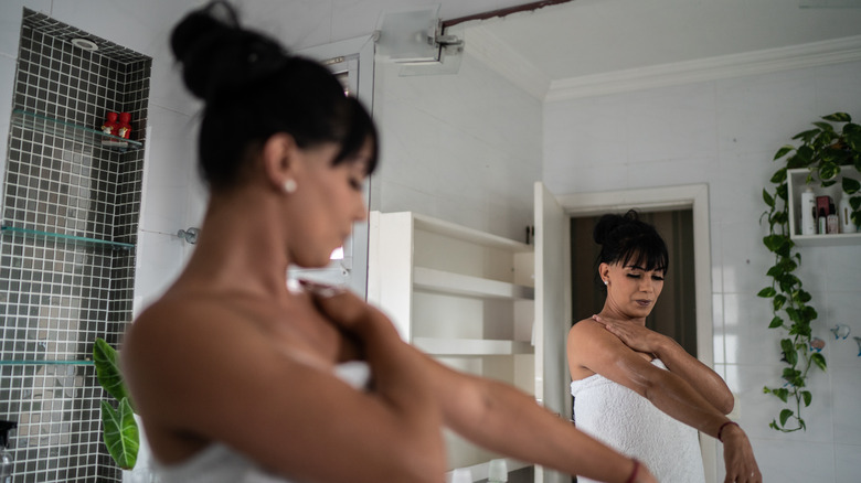 woman moisturizing arms after shower