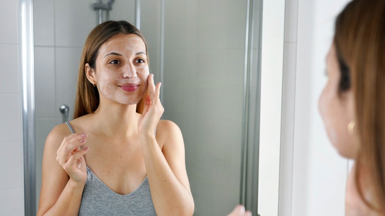 smiling woman applying skincare product