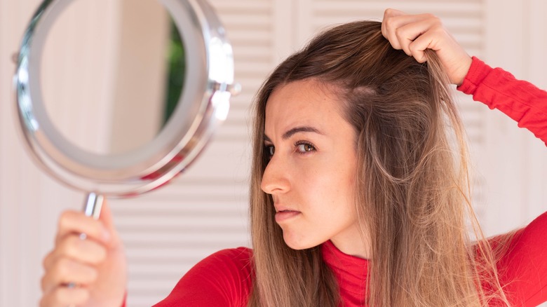 Woman looking at hair thinning in mirror