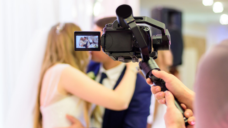 man filming wedding couple