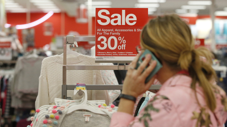A woman on her phone at Target in front of a sale sign