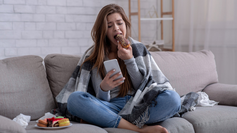 A woman eating while looking sad 