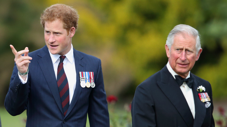 Prince Harry points something out to King Charles