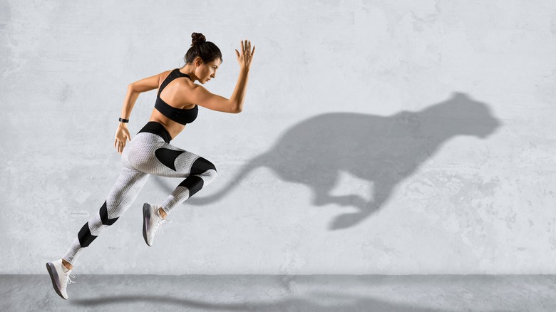 woman running next to shadow of a cheetah on a wall