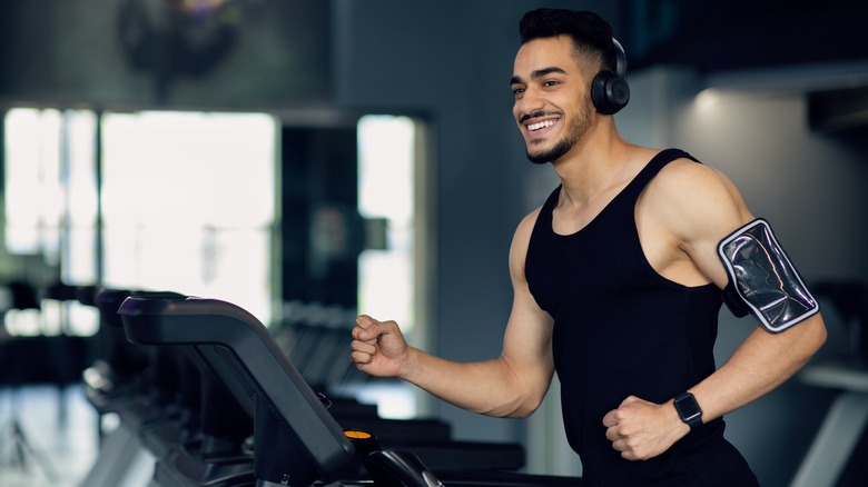 man running on treadmill smiling with headphones on