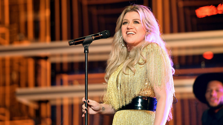 Kelly Clarkson holding a mic on stage