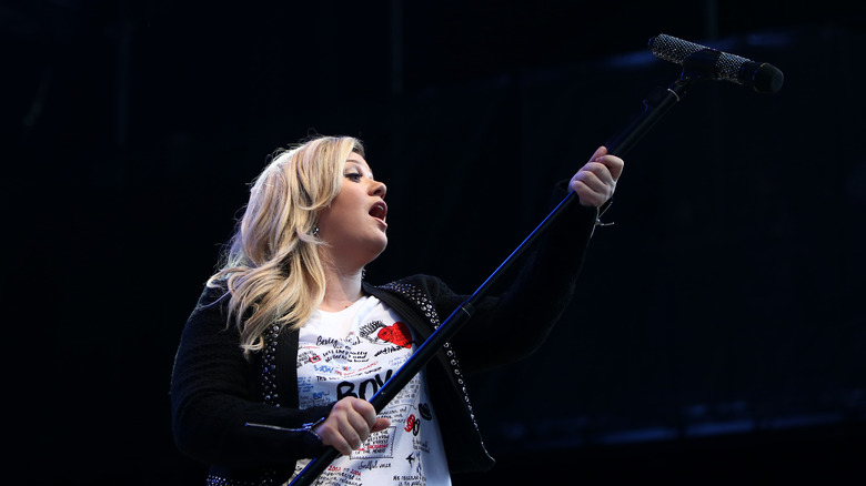 Kelly Clarkson holding mic out to audience