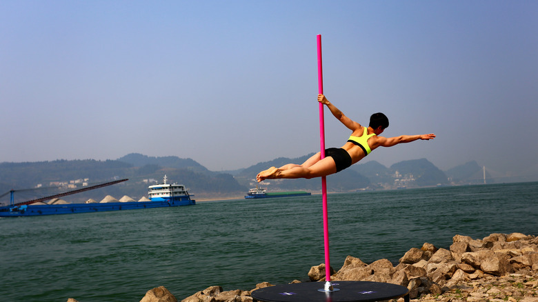 woman pole dancing outside in front of water