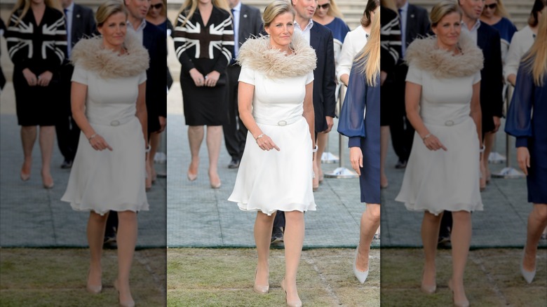 Duchess Sophie walking in a white dress with a feathered neckline