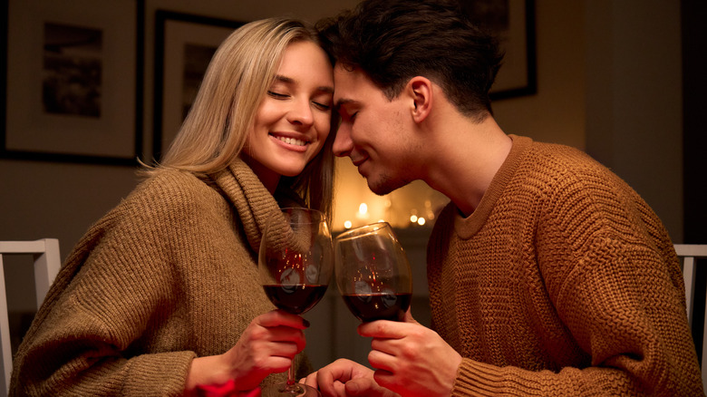 A young couple in matching sweaters press having a romantic dinner 