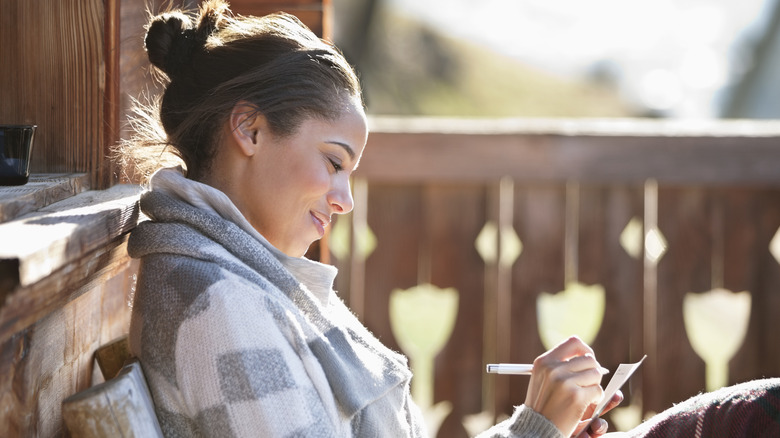 smiling woman sitting outside journaling