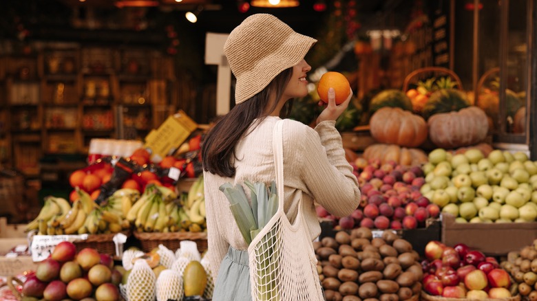 smiling woman holding fruit in market