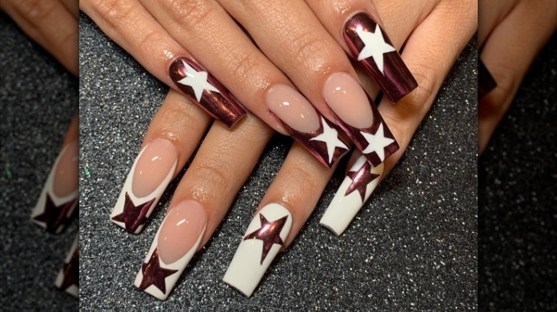 Nail art with chrome colored stars and white polish