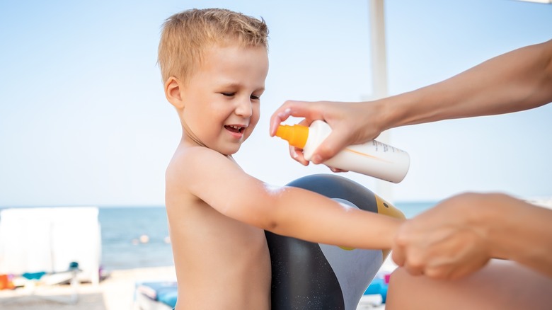 Child using spray-on sunscreen
