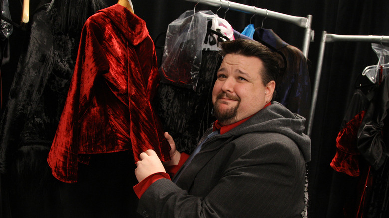 Chris March smiling as he holds clothes on rail backstage at fashion show