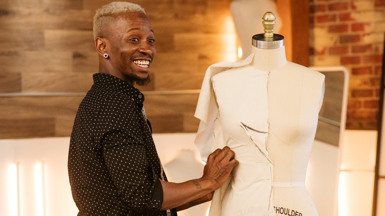 Sha'Vi Lewis smiling while pinning fabric to a mannequin