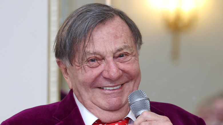 Barry Humphries smiling with microphone