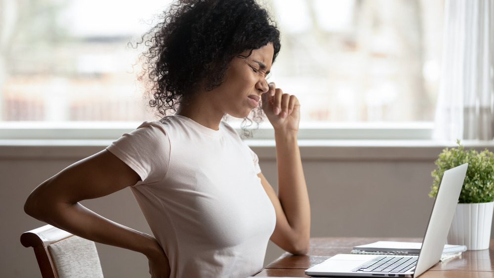 A woman sitting at a desk with back issues