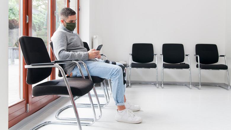 man sitting in a waiting room playing on his phone