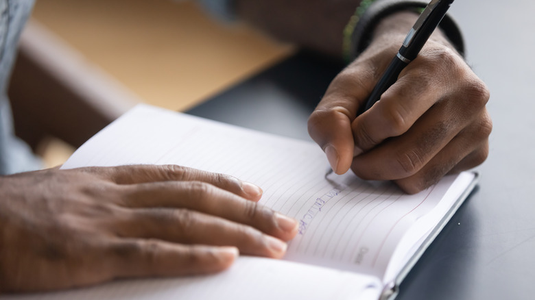 man writing on paper