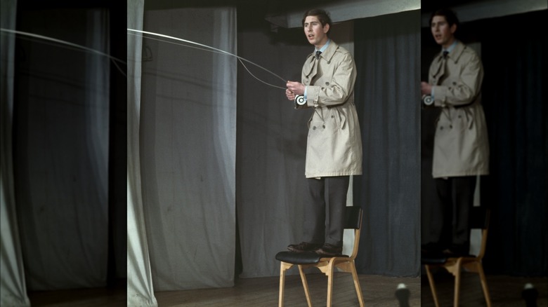 King Charles standing onstage pretending to fish