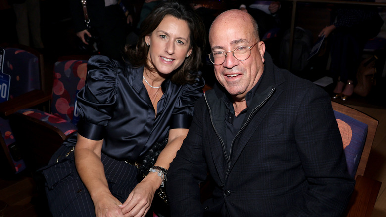 Jeff Zucker and girlfriend Allison Gollust sitting in an audience, leaning toward each other and smiling.