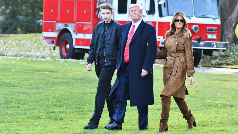 Donald Trump walks across a lawn with Melania and Barron