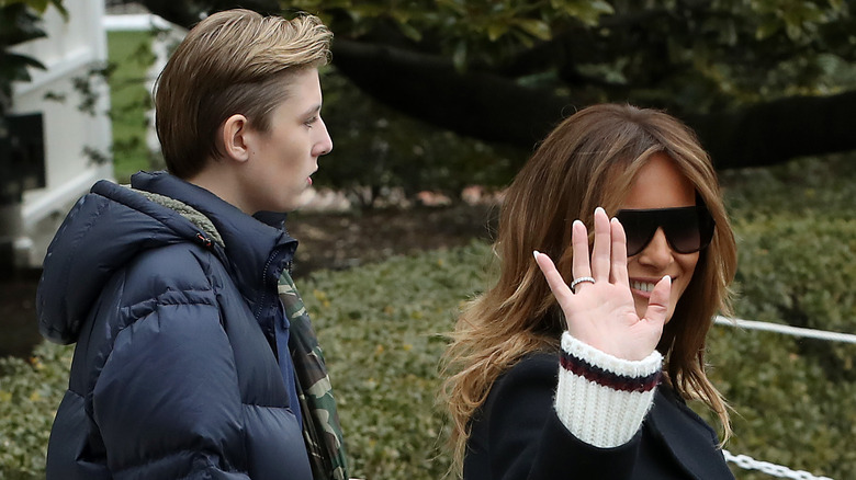 Melania Trump waves at the camera with Barron behind her