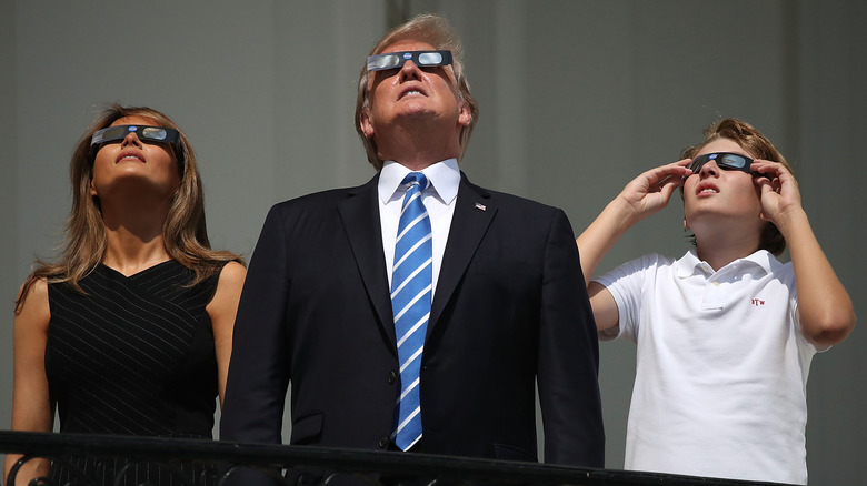 Donald Trump, along with Melania and Barron, look upward whiel wearing eclipse glasses