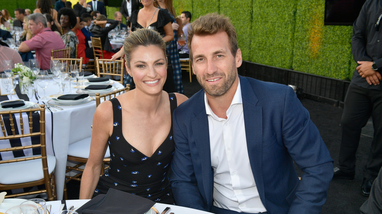 erin andrews and jarret stoll smiling while sitting at a table